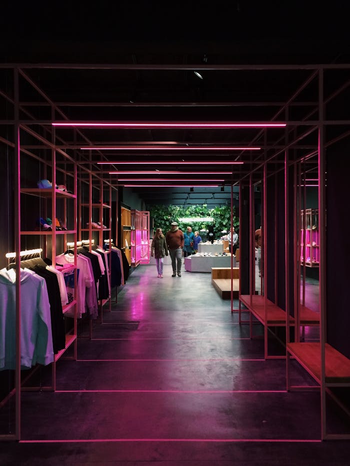 services-01 Interior of a modern clothing store in Antwerp, featuring neon pink lights and a sleek design.