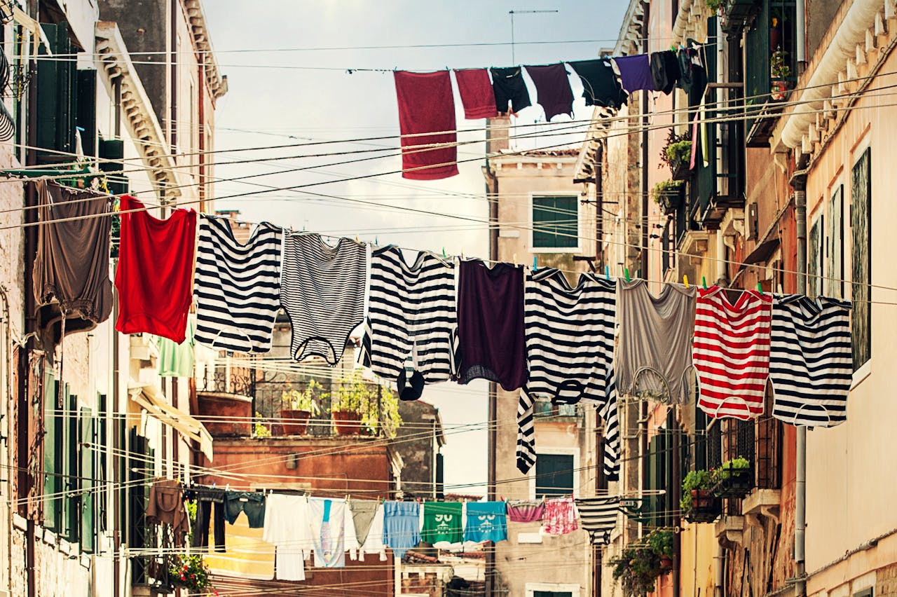 Vivid striped clothes hanging on lines between urban buildings.