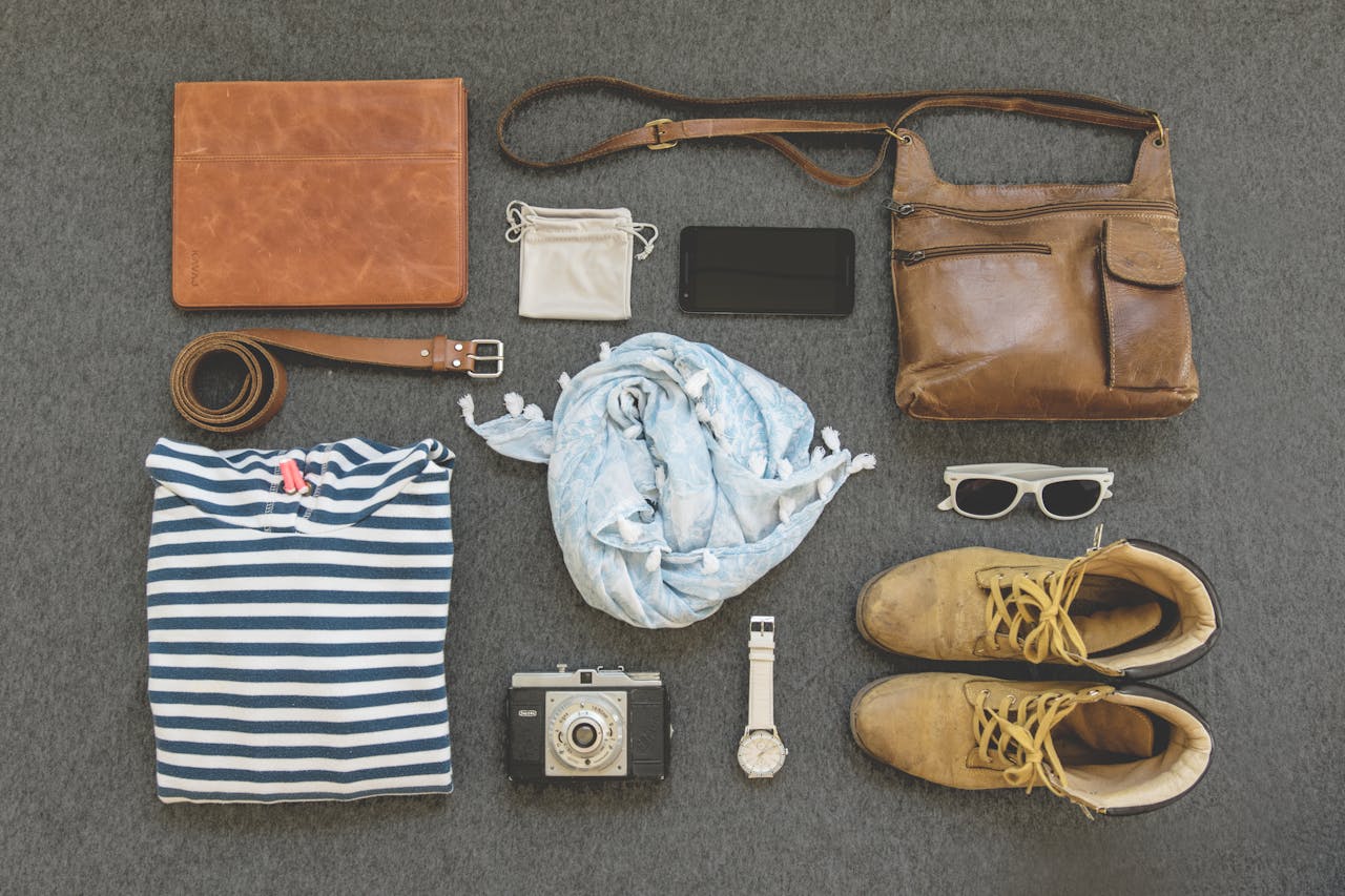 services-06 Vintage travel essentials flat lay with leather bags, shoes, camera, and clothing.