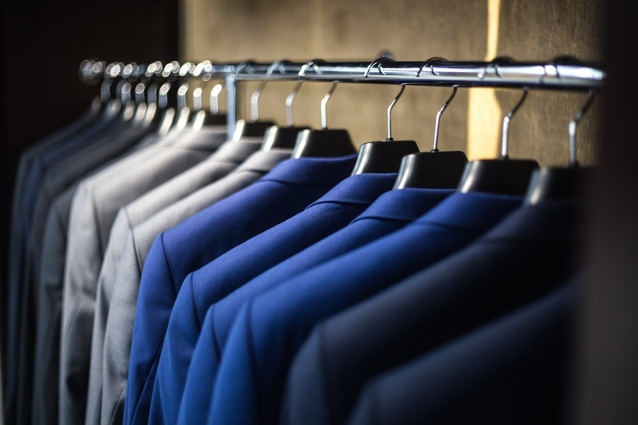 why-choose-us Close-up of neatly arranged suits in a wardrobe, showcasing fashion and organization.